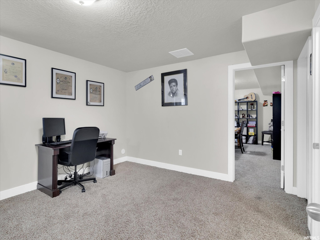 Home office featuring a textured ceiling and light carpet