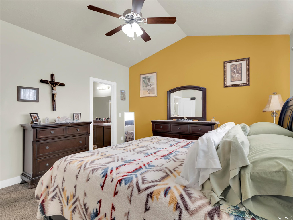Carpeted bedroom featuring ceiling fan, connected bathroom, and vaulted ceiling