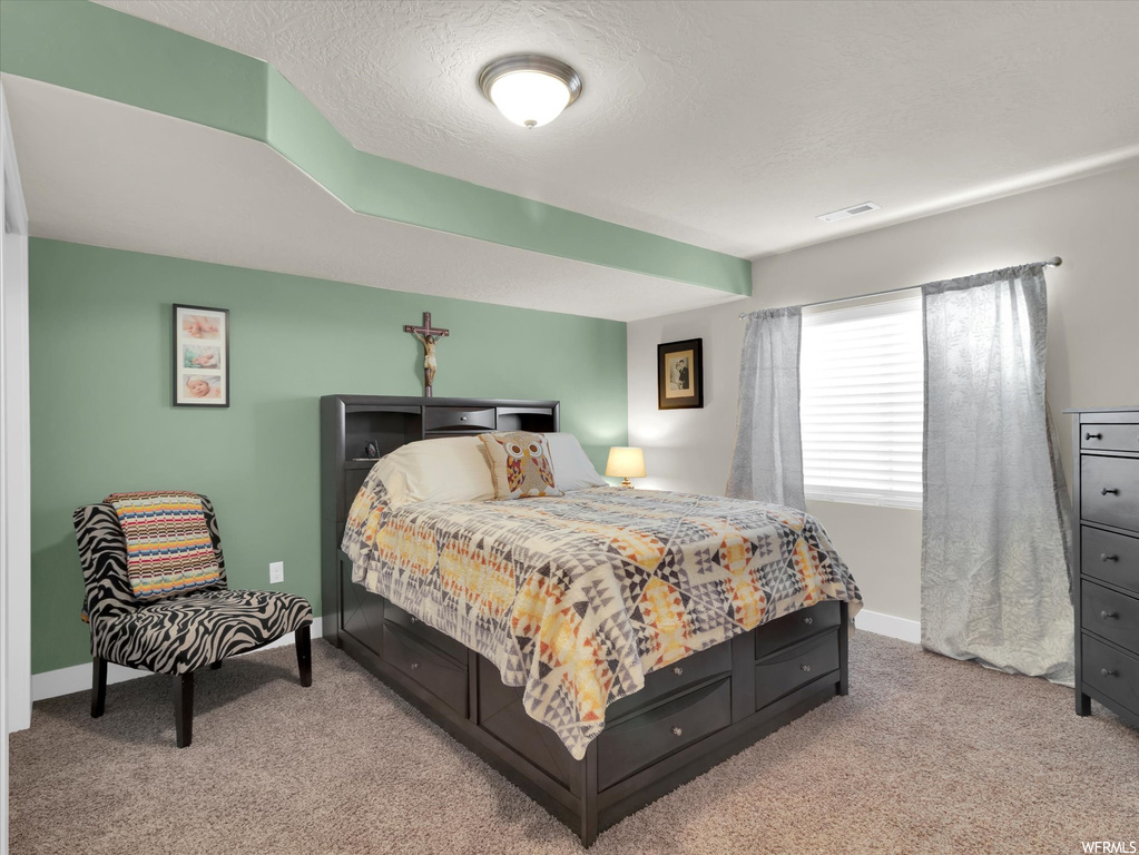 Bedroom featuring light carpet and a textured ceiling
