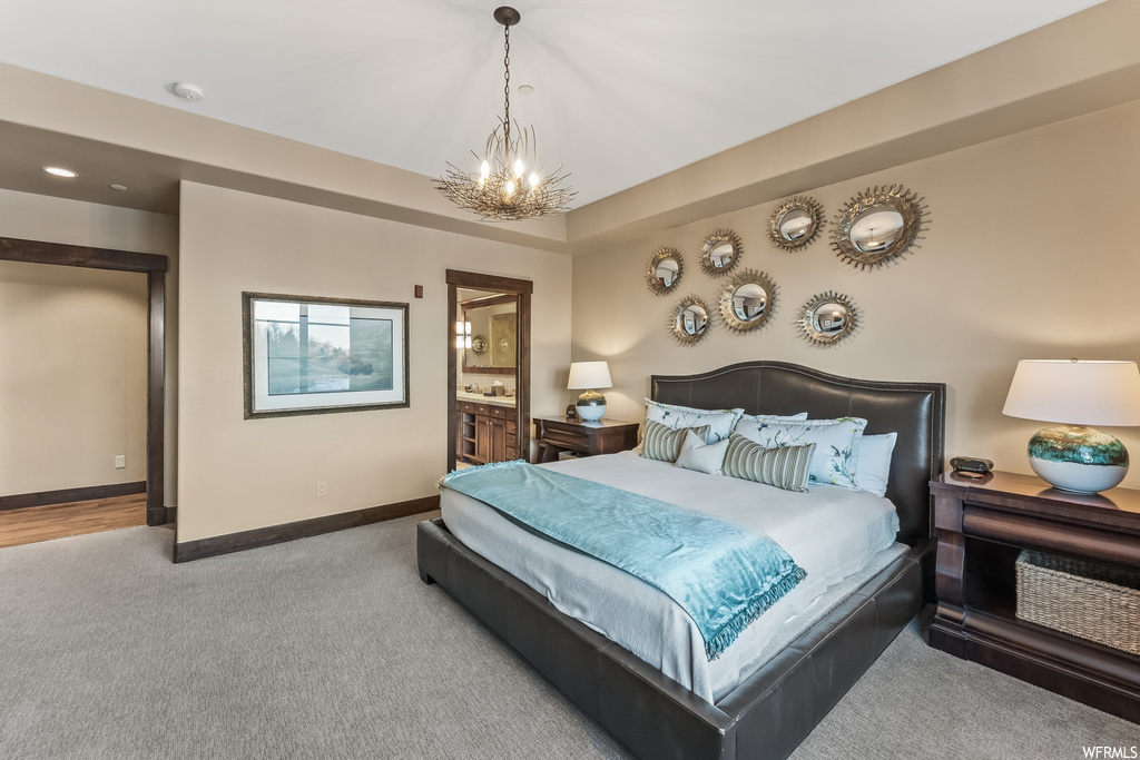 Bedroom featuring a notable chandelier, ensuite bath, and light hardwood / wood-style flooring