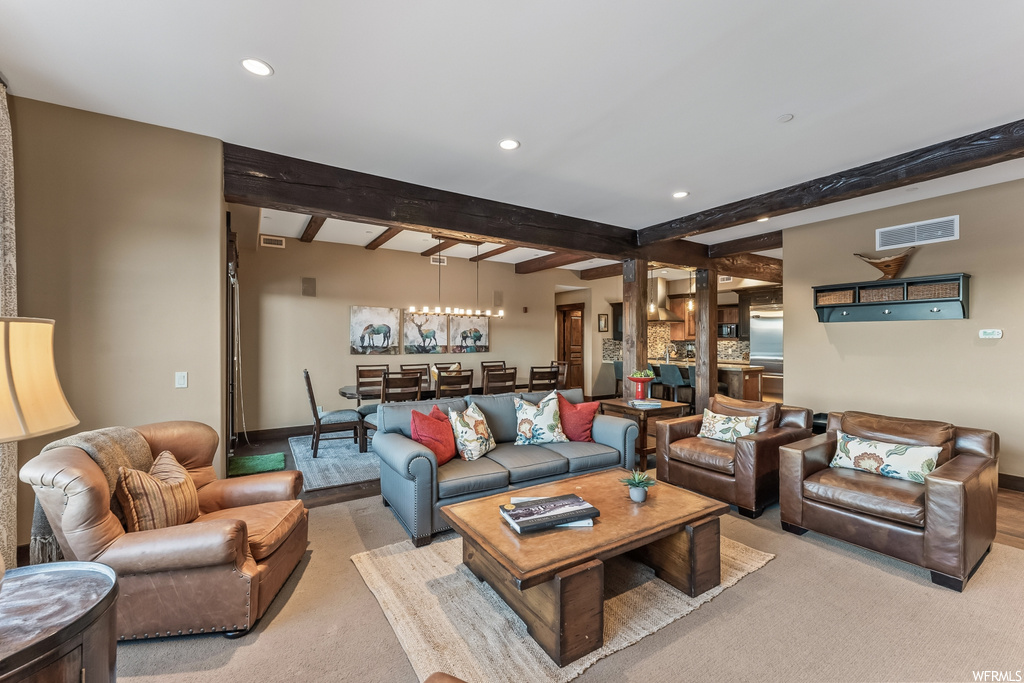 Carpeted living room featuring decorative columns and beam ceiling