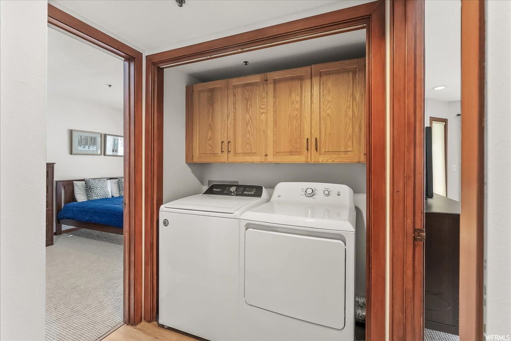 Laundry area with cabinets, washing machine and clothes dryer, and light colored carpet