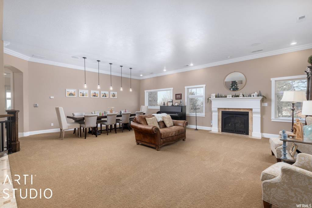 Living room with ornamental molding, a tile fireplace, and light colored carpet