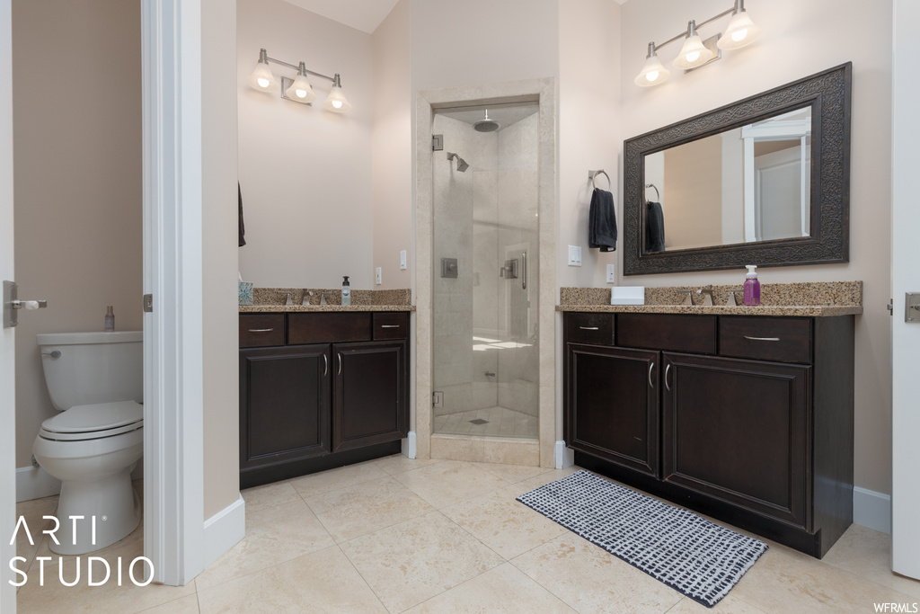 Bathroom with toilet, tile flooring, oversized vanity, and a tile shower