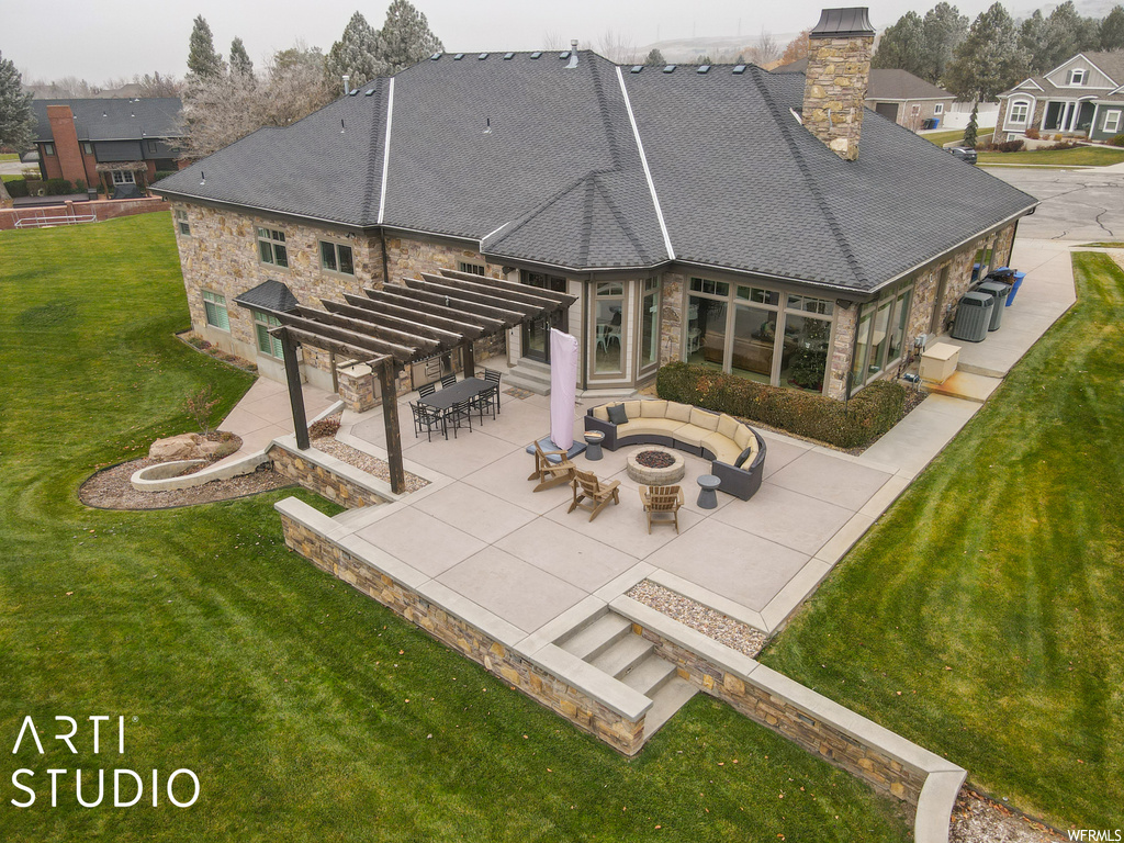 Rear view of house with a lawn, a patio, and an outdoor fire pit