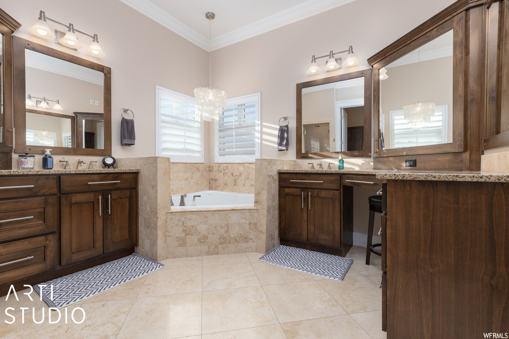 Bathroom featuring vanity, tile floors, tiled tub, and crown molding