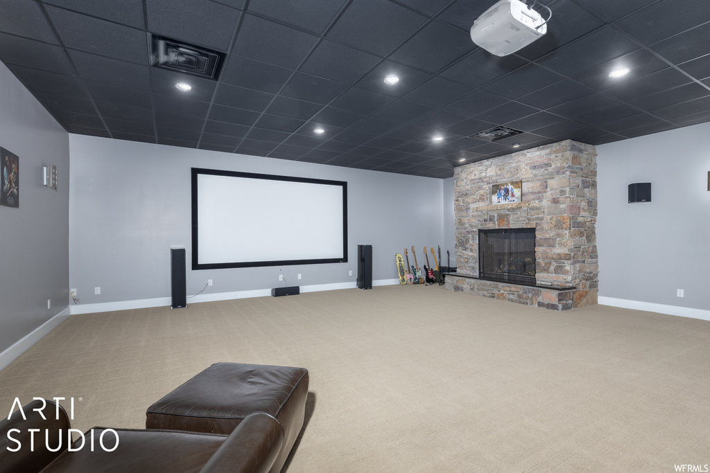Carpeted home theater room with a paneled ceiling and a fireplace