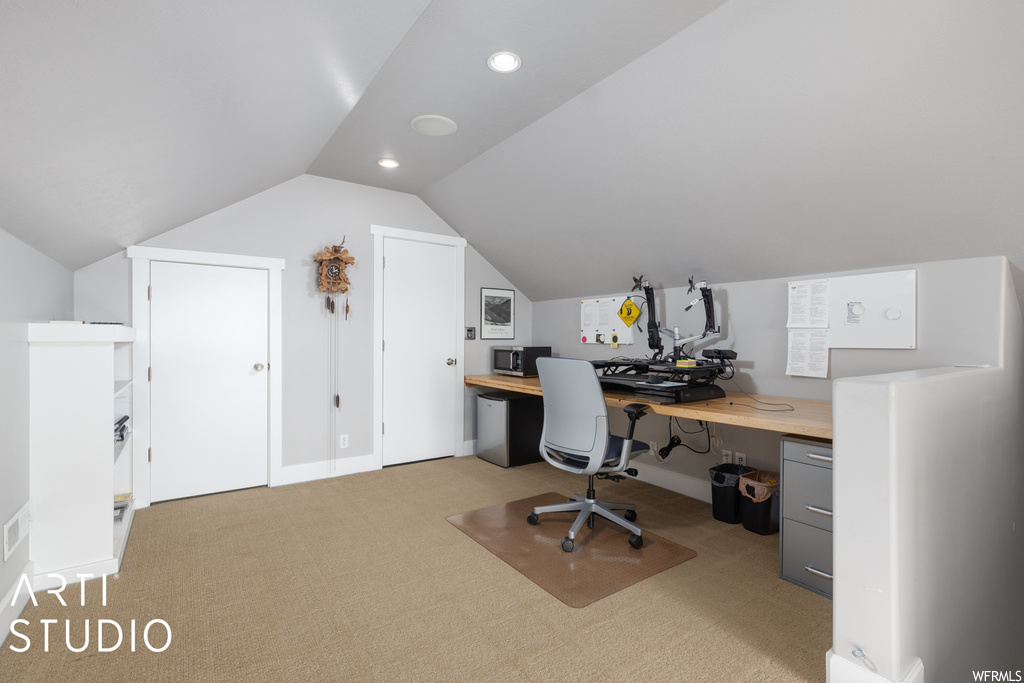 Carpeted office space with lofted ceiling