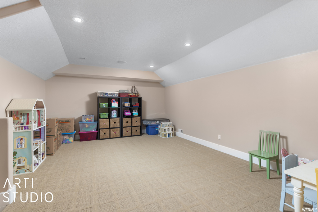 Game room with vaulted ceiling and light carpet