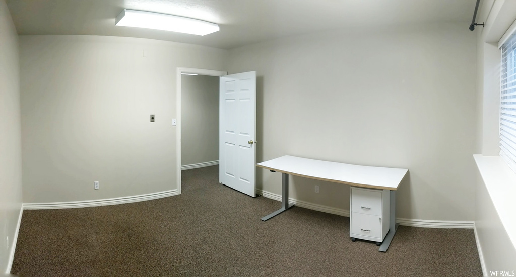 Unfurnished office featuring dark carpet