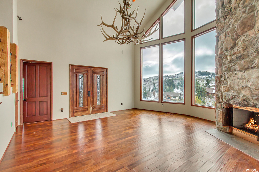 Foyer featuring high vaulted ceiling, a fireplace, a notable chandelier, and hardwood / wood-style flooring