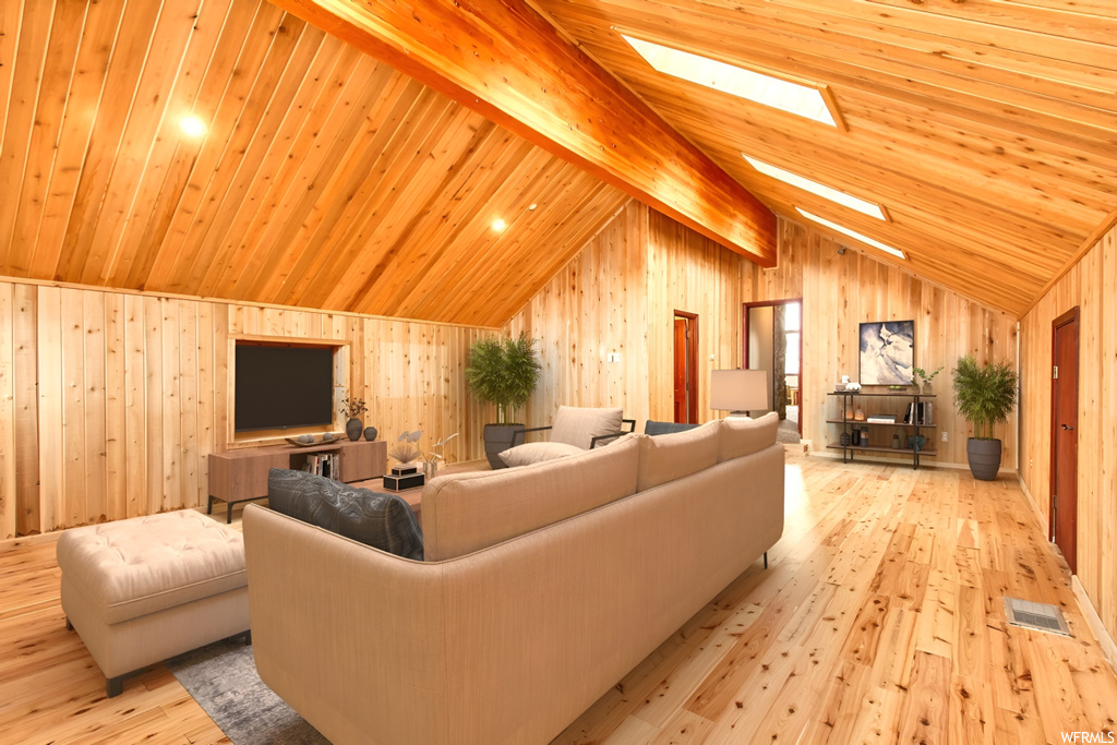 Living room with beamed ceiling, high vaulted ceiling, a skylight, light hardwood / wood-style flooring, and wood walls