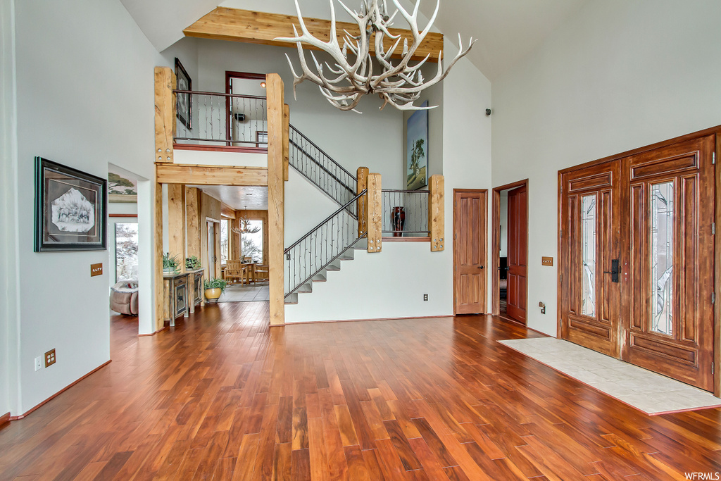 Foyer entrance featuring dark hardwood / wood-style floors, high vaulted ceiling, and a notable chandelier
