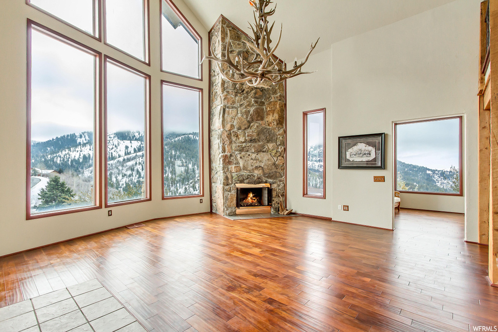 Unfurnished living room with high vaulted ceiling, light hardwood / wood-style floors, a fireplace, and a mountain view