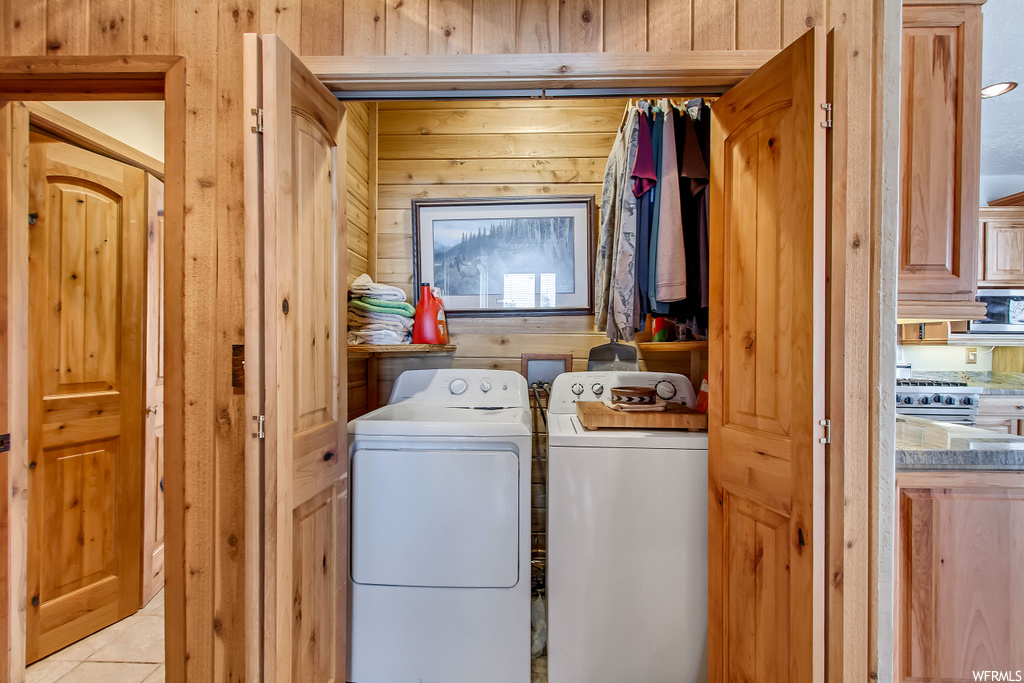 Laundry area with washer hookup, wood walls, light tile flooring, and washing machine and dryer