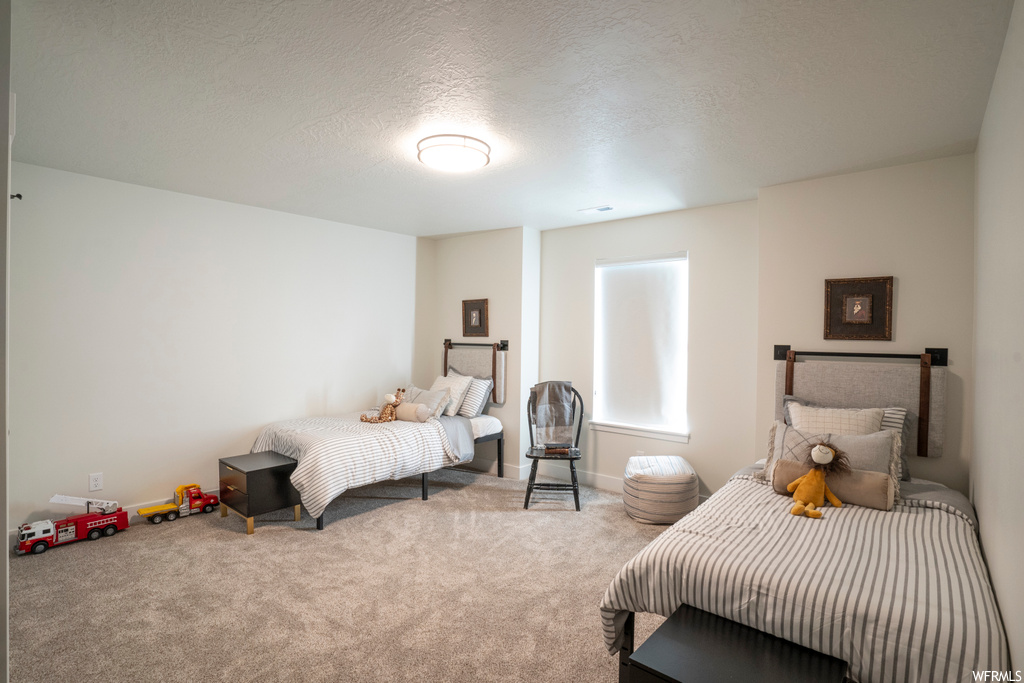 Bedroom featuring light colored carpet and a textured ceiling