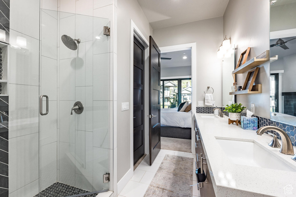 Bathroom with dual sinks, oversized vanity, walk in shower, and tile flooring