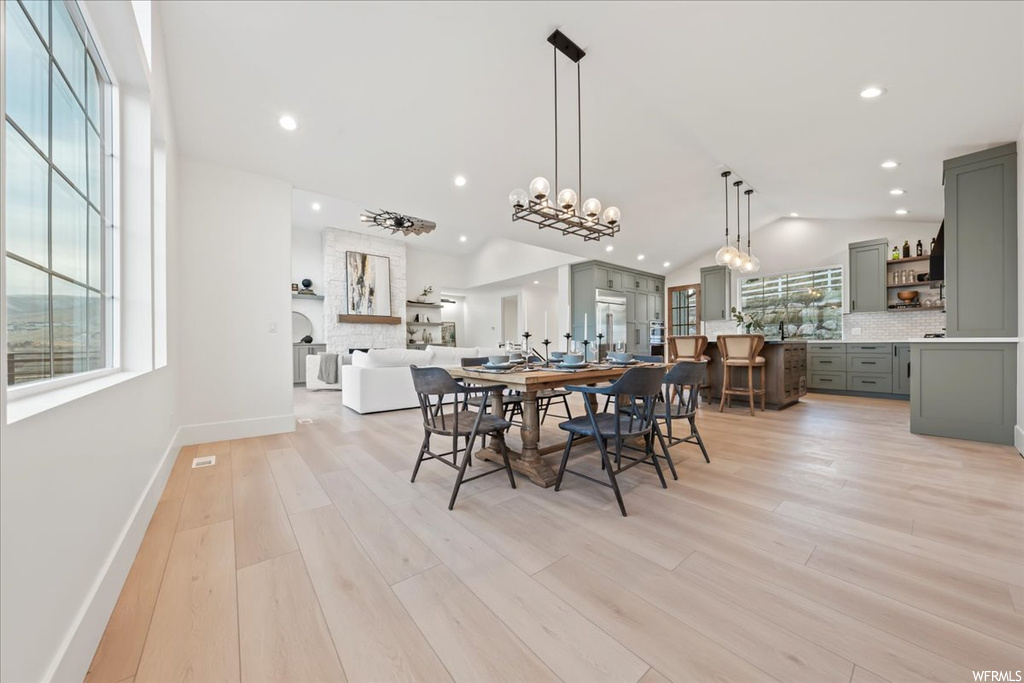 Dining area featuring light hardwood / wood-style flooring, a chandelier, and lofted ceiling