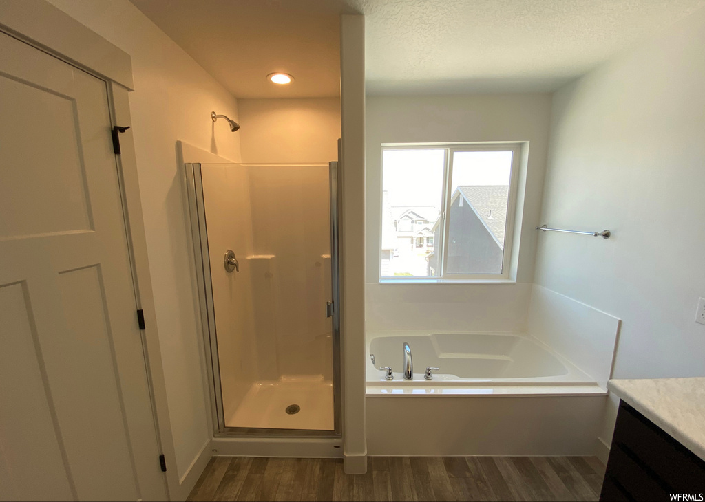 Bathroom featuring separate shower and tub, vanity, a textured ceiling, and wood-type flooring