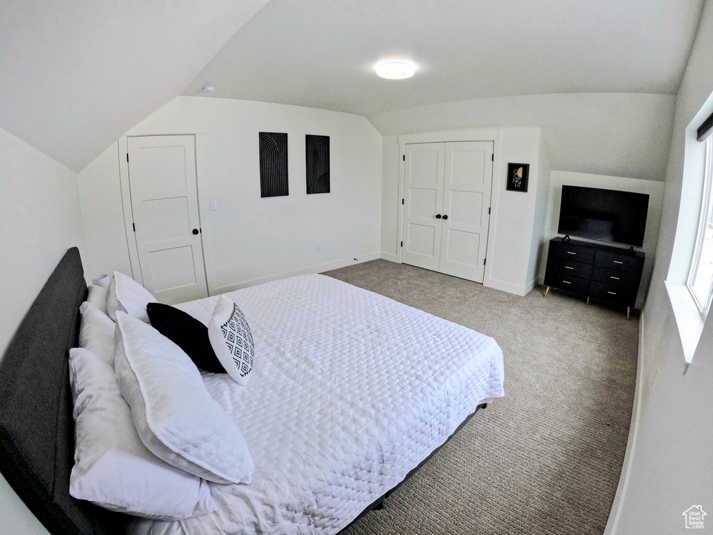 Bedroom with light carpet and vaulted ceiling