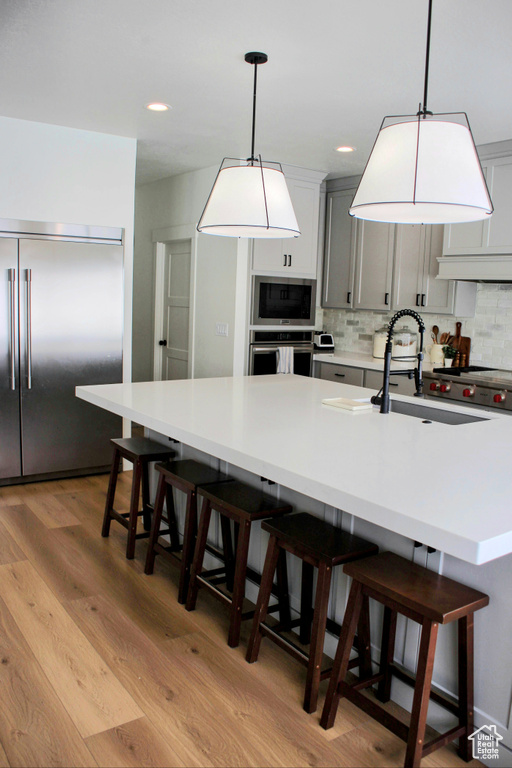Kitchen with light hardwood / wood-style flooring, tasteful backsplash, and decorative light fixtures