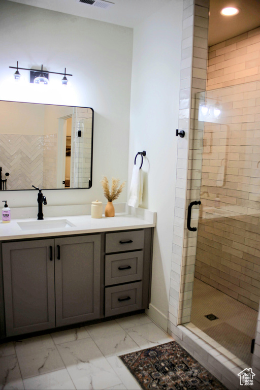 Bathroom featuring large vanity, tile floors, and a shower with shower door