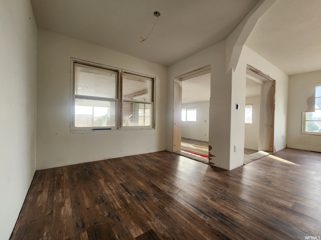 Spare room with dark hardwood / wood-style flooring and a healthy amount of sunlight