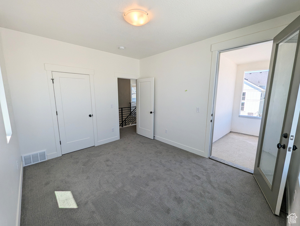 Unfurnished bedroom featuring light colored carpet, french doors, and a closet