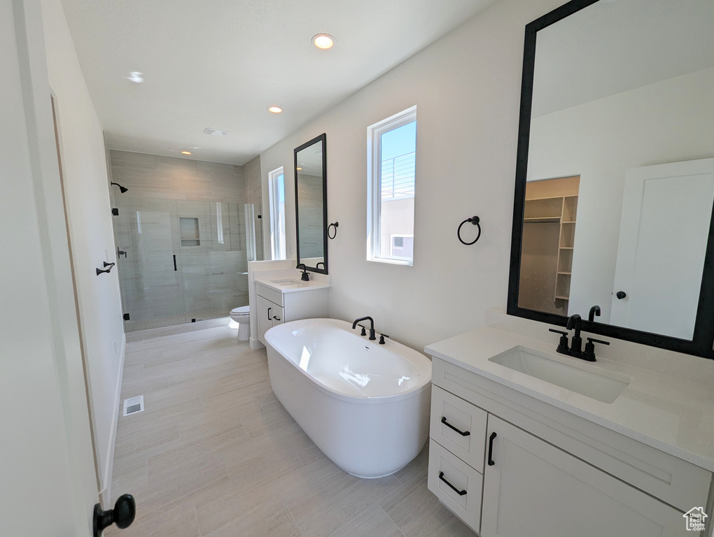Full bathroom featuring tile floors, independent shower and bath, toilet, and vanity with extensive cabinet space