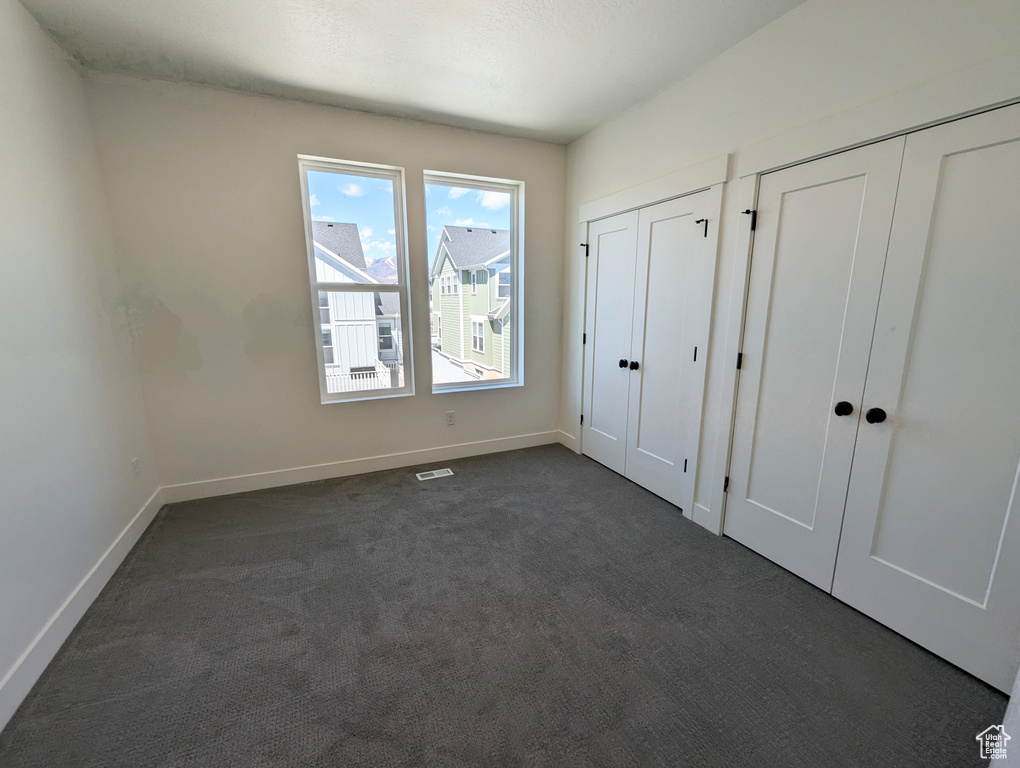 Unfurnished bedroom with dark carpet and multiple closets