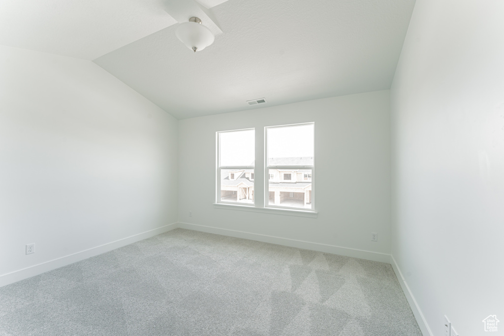 Empty room with light carpet and vaulted ceiling