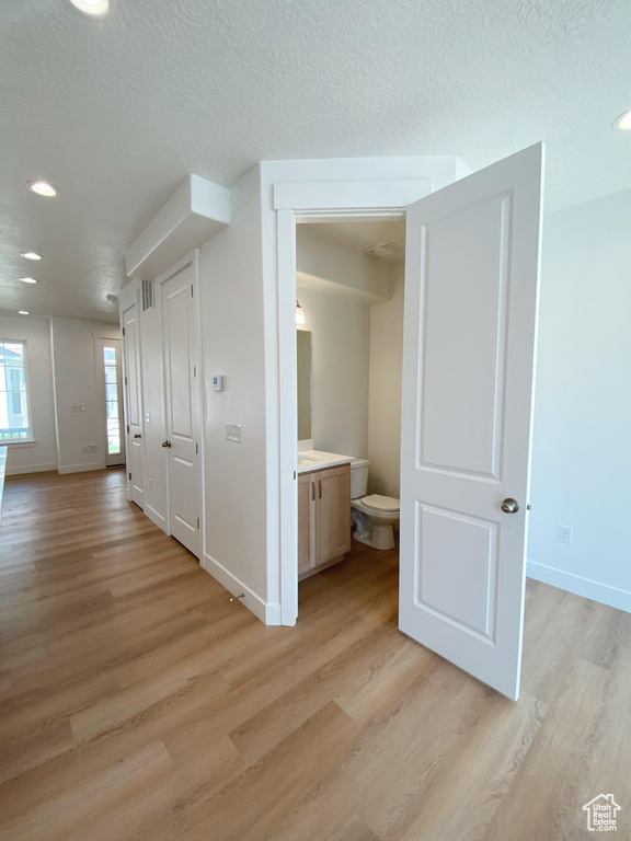 Hall with light hardwood / wood-style floors and a textured ceiling