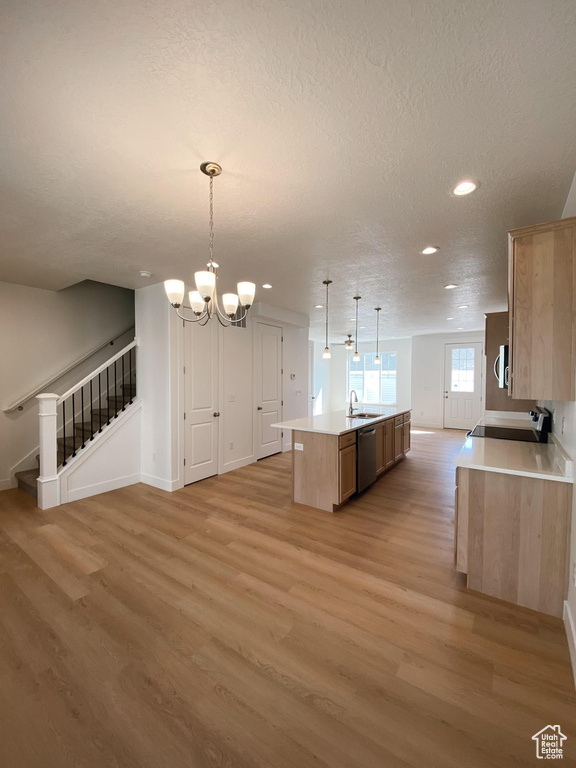 Kitchen with a chandelier, light wood-type flooring, dishwasher, a kitchen island with sink, and hanging light fixtures