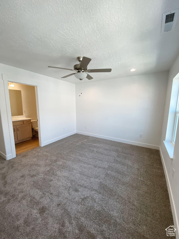 Unfurnished bedroom with a textured ceiling, connected bathroom, carpet floors, and ceiling fan