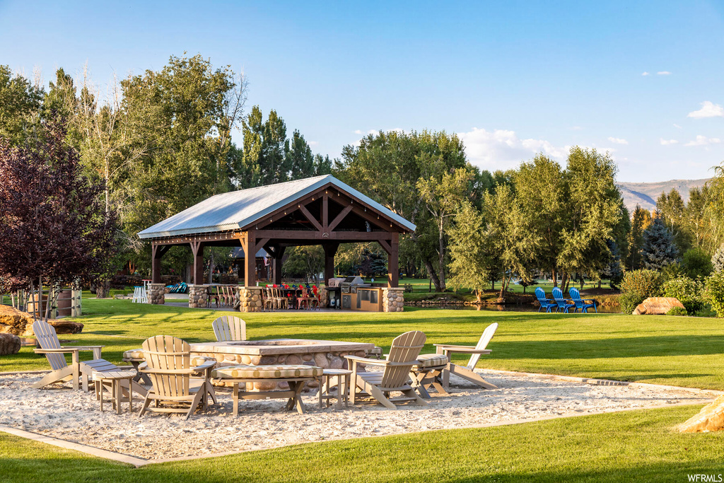 Surrounding community with a lawn, an outdoor fire pit, and a gazebo