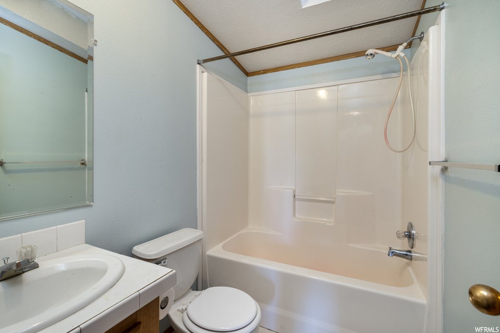 Full bathroom featuring toilet, large vanity, a textured ceiling, and shower / bath combination