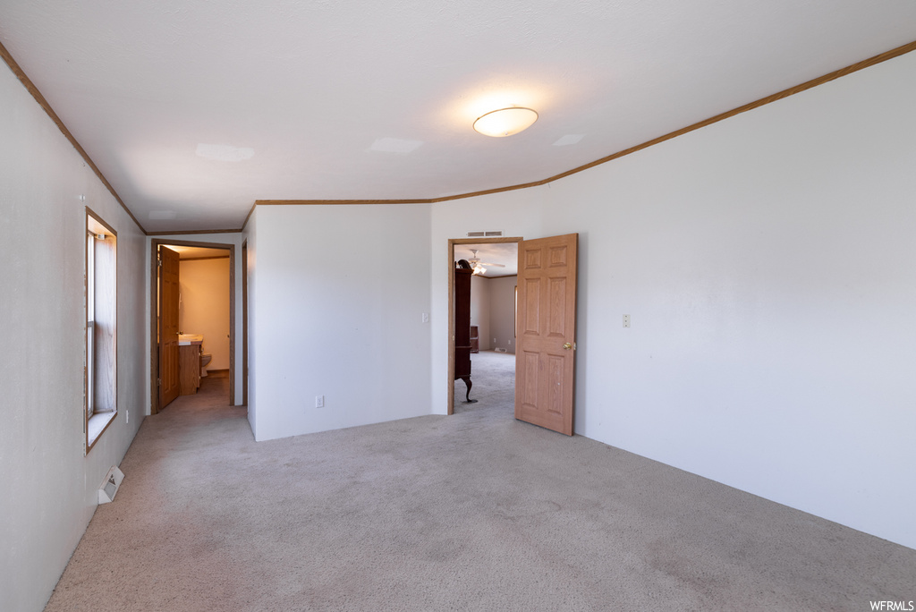 Empty room with crown molding and light carpet