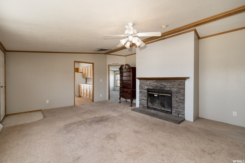 Unfurnished living room with ceiling fan, a fireplace, light colored carpet, ornamental molding, and lofted ceiling