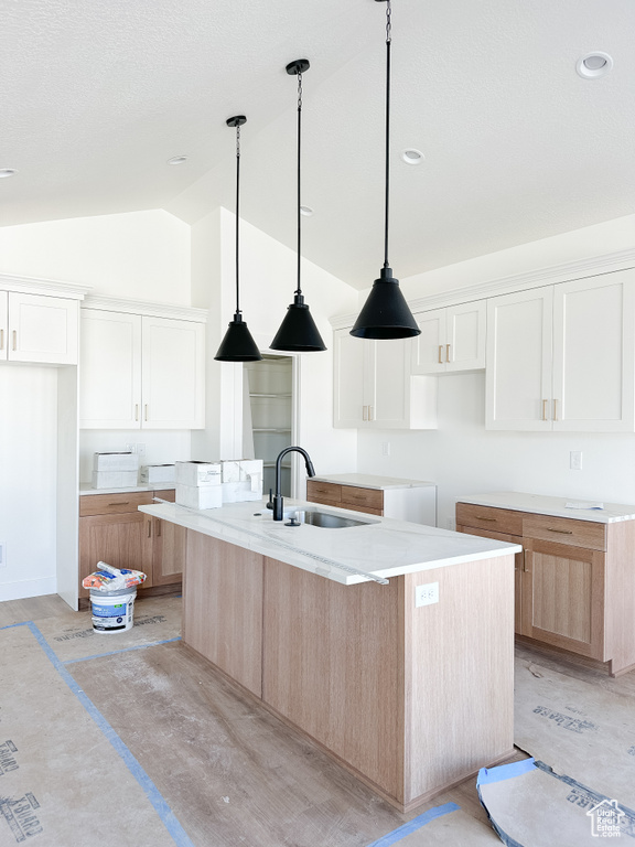Kitchen with white cabinetry, sink, vaulted ceiling, and a kitchen island with sink