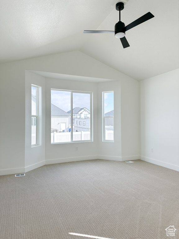 Spare room featuring light colored carpet, lofted ceiling, and ceiling fan