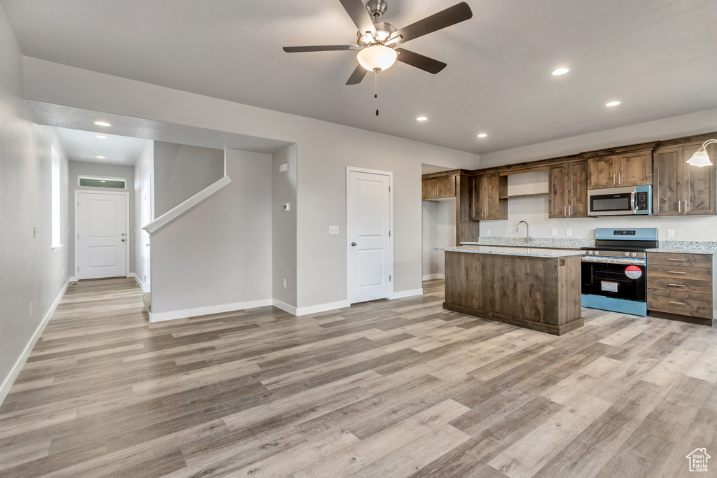 Kitchen featuring light hardwood / wood-style flooring, stainless steel appliances, sink, ceiling fan, and an island with sink
