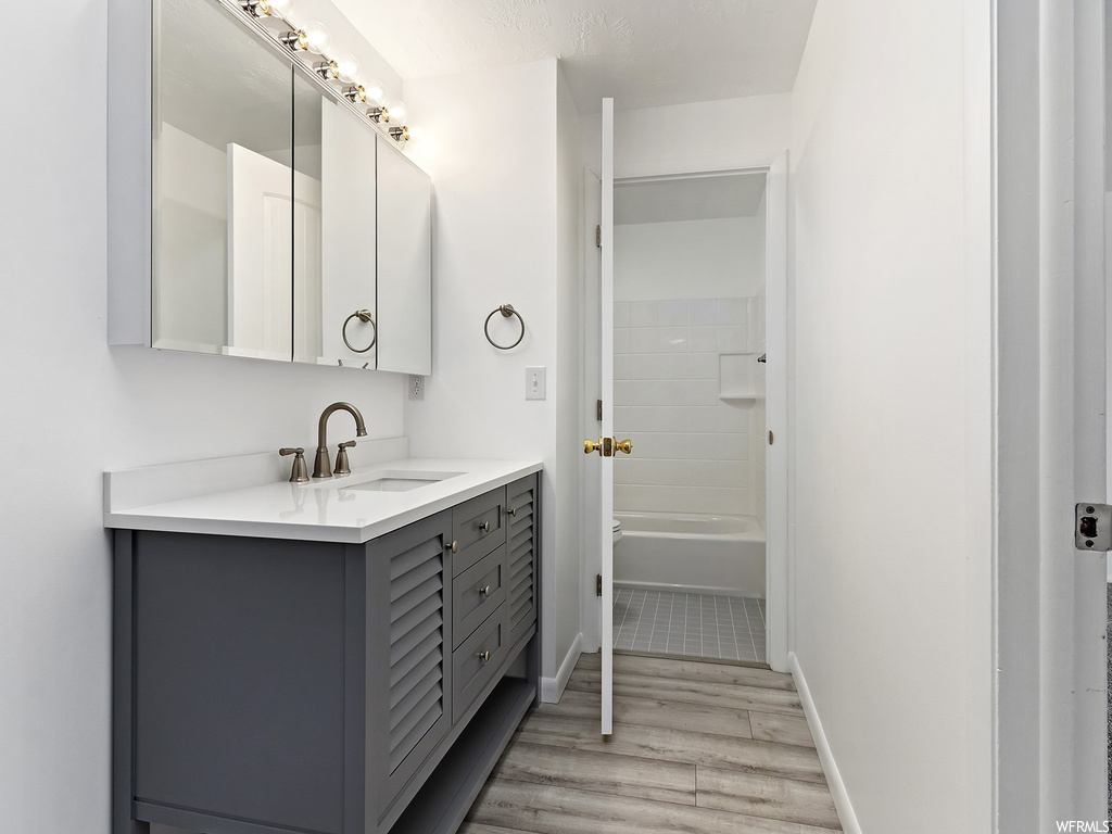 Bathroom featuring vanity, tiled shower / bath, and hardwood / wood-style flooring