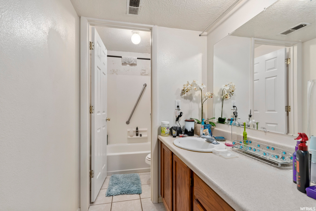 Full bathroom featuring toilet, a textured ceiling, shower / washtub combination, tile floors, and vanity