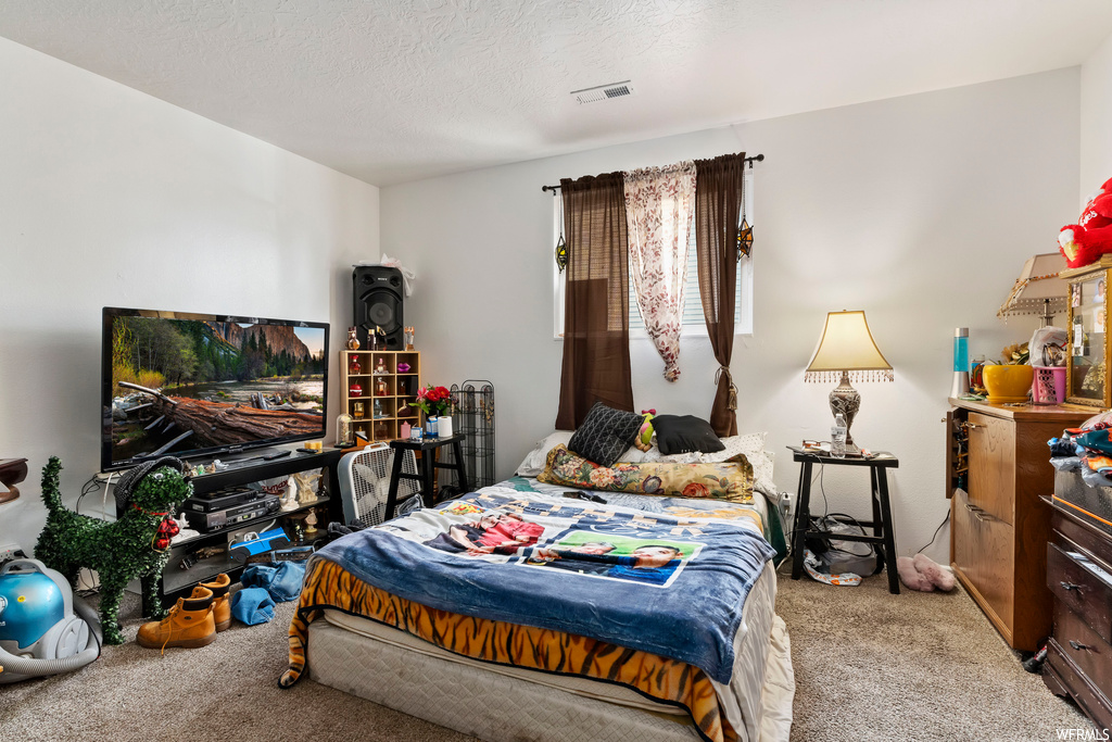 Bedroom featuring light carpet and a textured ceiling