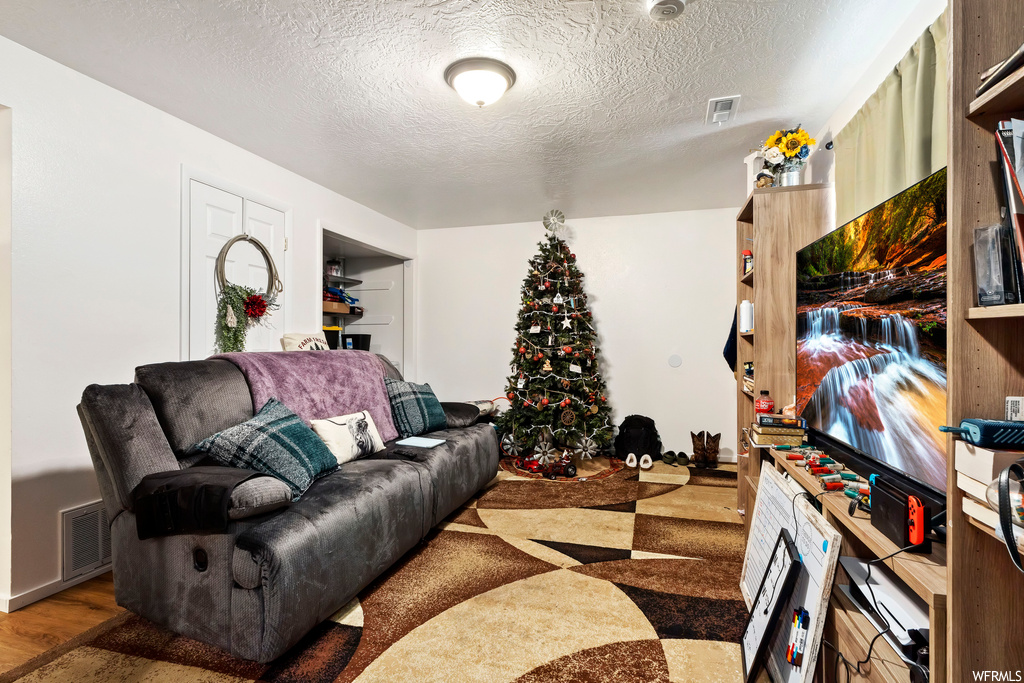 Living room with a textured ceiling and hardwood / wood-style flooring
