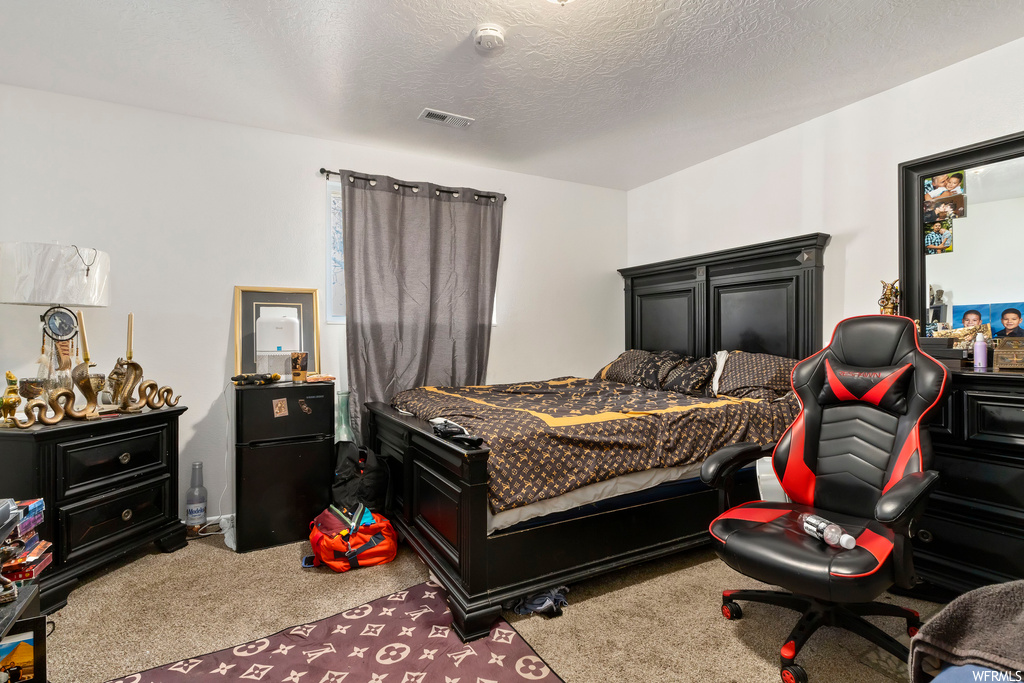 Bedroom featuring light colored carpet and a textured ceiling
