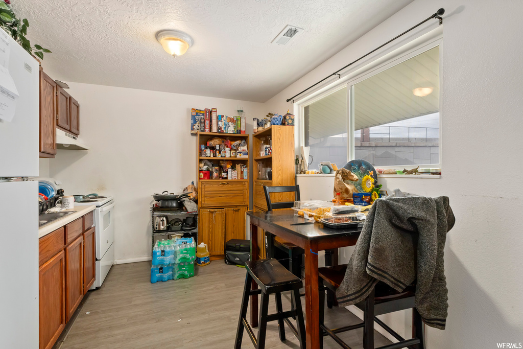 Dining space with a textured ceiling and light wood-type flooring