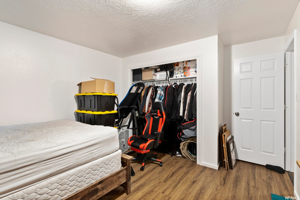 Bedroom featuring a closet, a textured ceiling, and wood-type flooring