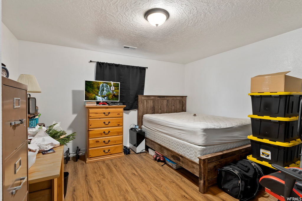 Bedroom featuring a textured ceiling and light hardwood / wood-style flooring