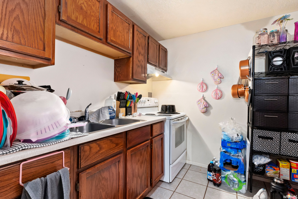 Kitchen featuring light tile floors, electric range, and sink